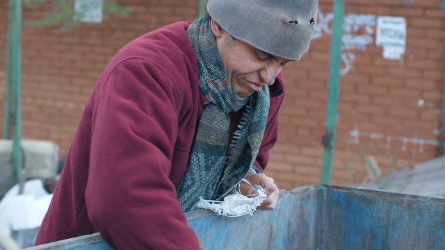 Homeless man in the trash looking for food