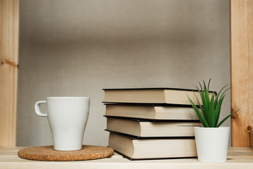 A stack of books on the shelf. Books and a mug of tea on the shelf.