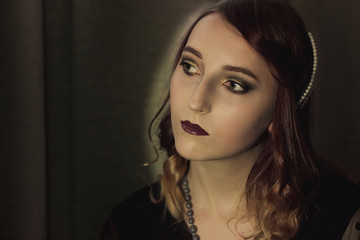 Portrait of a young woman in the style of the 20s. Vintage makeup and hairstyle.