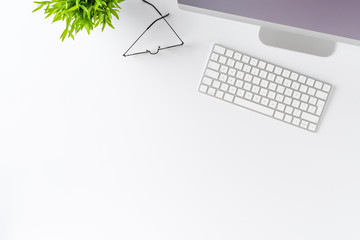 Overhead shot of computer with accessories on white table. Office desktop concept. Flat lay