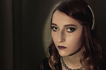 Portrait of a young woman in the style of the 20s. Vintage makeup and hairstyle.