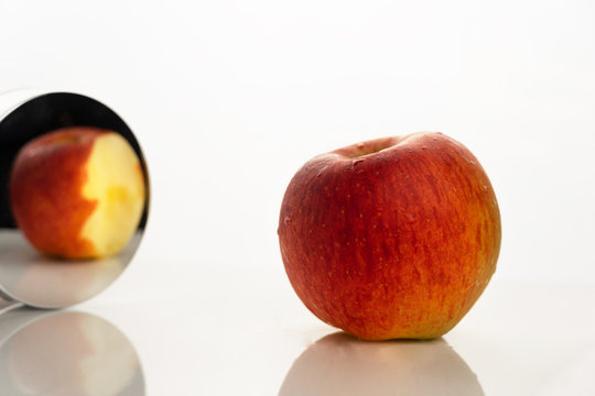 red orange apple fruit for food in the mirror in paradox reality concept on white background