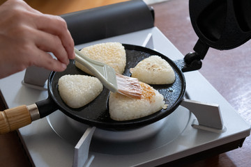 自宅で作る焼きおにぎり　焼きおにぎり器で焼いているおにぎりに刷毛でだし醤油を塗る様子
