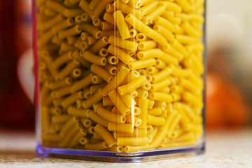 raw italian macaroni pasta inside clear storage container