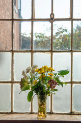Painterly faded flowers by old window