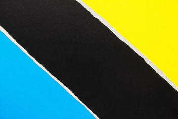 Yellow, blue and black torn sheet of cardboard paper with diagonal border texture background. Copy space for text message.