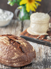 Freshly baked homemade bread, closeup. The concept of a healthy diet made from natural products, traditional craft bread cooked with natural sourdough. Sourdough and flour in the background