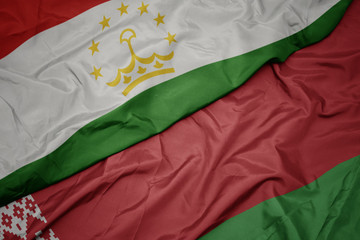 waving colorful flag of belarus and national flag of tajikistan.