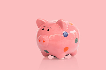 Pink ceramic piggy bank on pink background, saving money concept