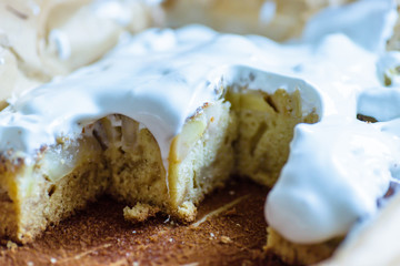 cut homemade fresh apple pie covered with white icing in baking tray with baking paper in it