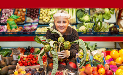 Woman in fruit and vegetable shop delivering a bouquet of artichokes and asparagus during corona virus outbreak