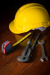 Fototapeta premium Metal wrench with tape measure and engineer helmet on table.