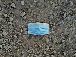 Disposable blue medical mask thrown on the ground, environmental pollution during coronavirus outbreak