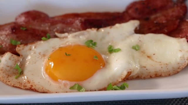 Spreading chopped green parsley over eggs and bacon 
