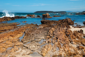 Fototapeta na wymiar Tomakin Australia, view of rock outcrop looking out to sea with island on the horizon