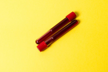 Two test tubes with blood isolate on yellow background. Concept medicine, the fight against viruses and bacteria, diseases