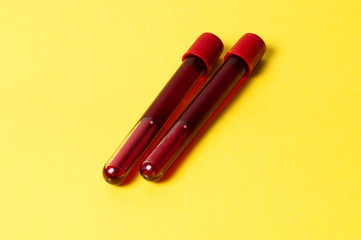 Two test tubes with blood isolate on yellow background. Concept medicine, the fight against viruses and bacteria, diseases