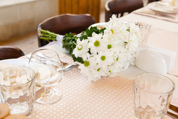 prepared tables for the celebration with tables and equipment decorated with flowers in a restaurant