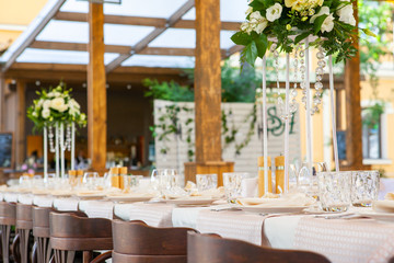 prepared tables for the celebration with tables and equipment decorated with flowers in a restaurant