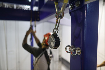 Close up pictures of stainless steel anchor point on structure pole and defocused abseiler using an...