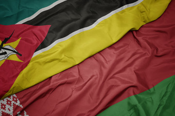 waving colorful flag of belarus and national flag of mozambique.