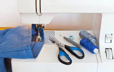 Sewing at home. Processing the bottom of denim pants. Hemming jeans on sewing machine. Close-up