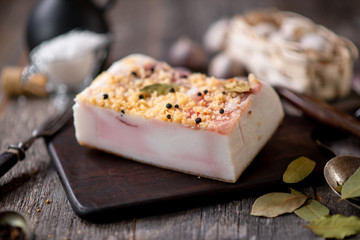 Salted lard with spices on wooden board with garlic pepper jar wooden