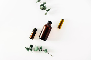 Two bottles of fragrant cosmetic or essential oil on a white background surrounded by sprigs of...