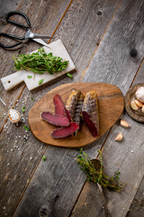 Salted basturma beef jerky on wooden board with rosemary green garlic