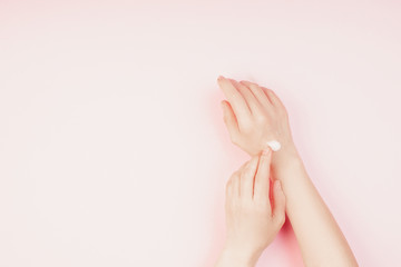 Woman moisturizing her hand with cosmetic cream, concept for feminine blog, social media, beauty concept