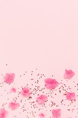 Frame of flowers and gold confetti on pink background. Spring Holidays, Birthday, Mothers Day, wedding. Copy space.