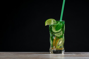 Citrus fruit and herbs in glass on wooden board, dark background