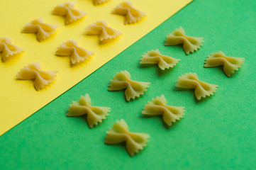 Italian pasta pattern on a blue background. Various colors of bow tie farfalle pasta viewed from above. Top view.