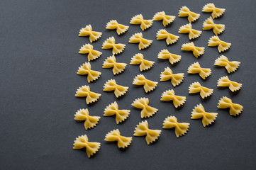 Italian pasta pattern on a blue background. Various colors of bow tie farfalle pasta viewed from above. Top view.