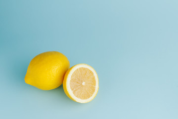 Cut half and whole fresh lemons on blue background