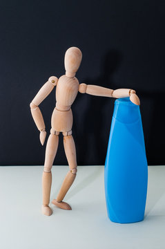 plastic bottle without water and wooden mannequin on black background