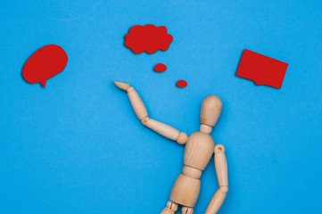 Wooden figurine holding blank placard against color background