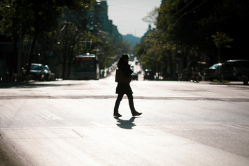 Silhouette of a woman crossing a road in downtown Bucharest during the covid-19 lockdown at dusk.