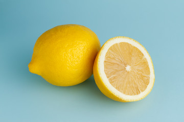 Closeup of freshly cut half and whole lemons on blue background