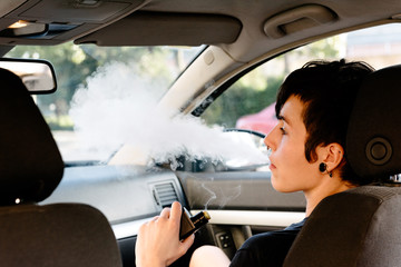 young woman vaping inside a car. used an electronic cigarette to quit smoking. Alternative to...