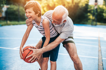 Grandfather and his grandson playing basketball.