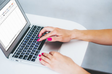 Female hands working on modern laptop. Office desktop on white background. Close-up partial view of woman holding credit card and using laptop at home 


