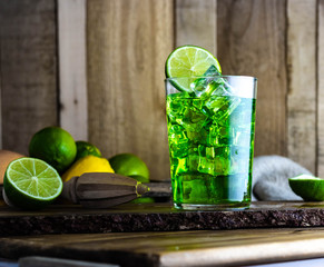 Refreshing green cocktail with lime and lemon on a wooden table