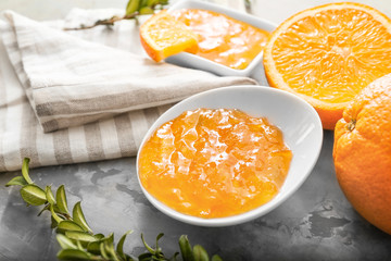 Plate with orange jam on grey background