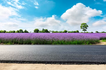 Gordijnen Empty asphalt road and purple lavender field on a sunny day. © ABCDstock
