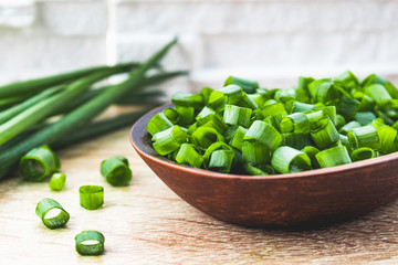 Sliced green onion rings in a wooden spoon on the table.