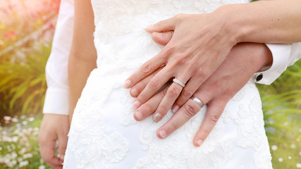 Obraz na płótnie Canvas Alliances de mariage en or, diamant et argent. Mains du couple sur la robe de mariée lors d'un mariage champêtre. Célébration de l'amour dans un parc.