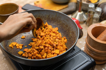hand cooking turmeric and ginger for jamu herbal drink