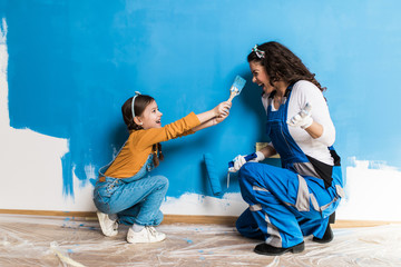 Fototapeta Mother and daughter enjoying together while painting wall. obraz