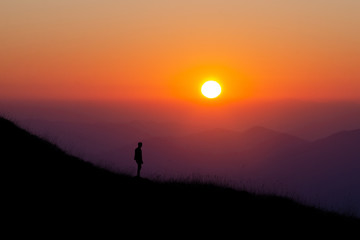 A young boy traveler stand and open arms and enjoy with beautiful sunset on top of the mountain.